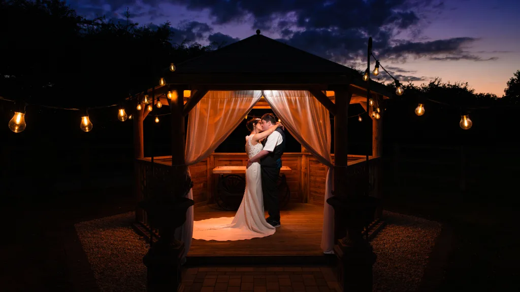 Couple sharing a kiss in a gazebo at sunset at Willerby Barn wedding in East Yorkshire