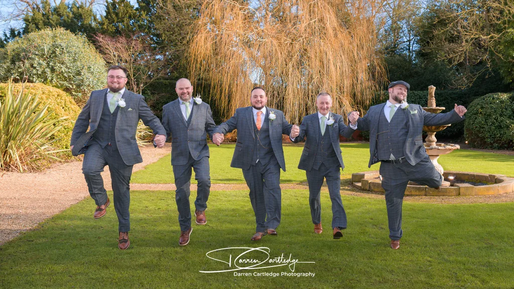 Groom and groomsmen skipping across the grounds of Bawtry Hall, South Yorkshire