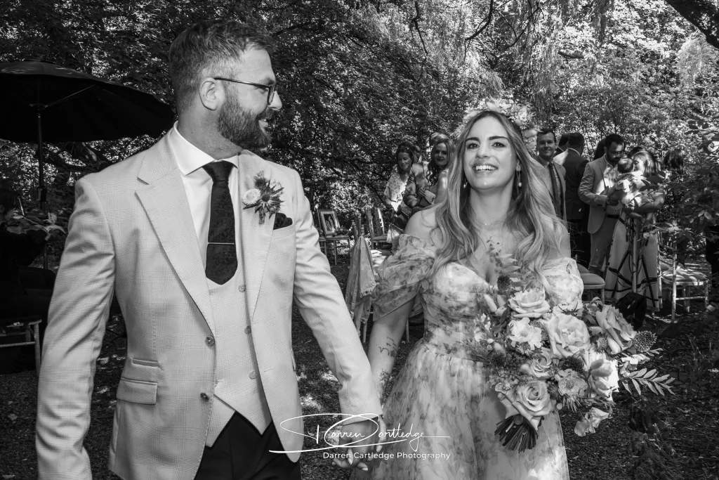 Bride and groom leaving a woodland wedding ceremony hand in hand at a Yorkshire wedding