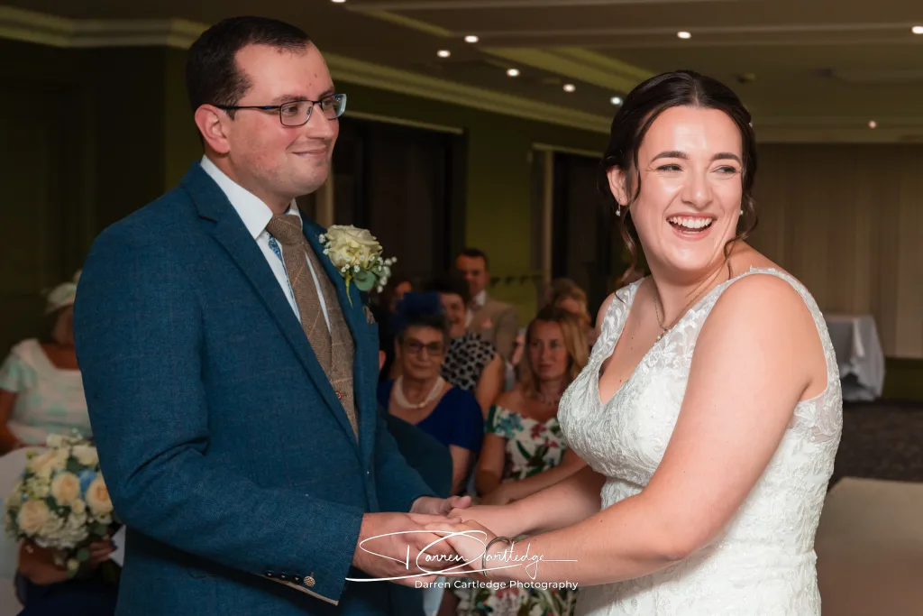 Bride laughing as groom looks on during the wedding ceremony at a Yorkshire wedding