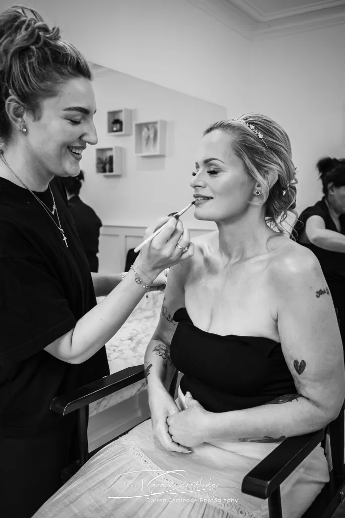Makeup artist applying lipstick to bride during morning preparations at a Yorkshire wedding