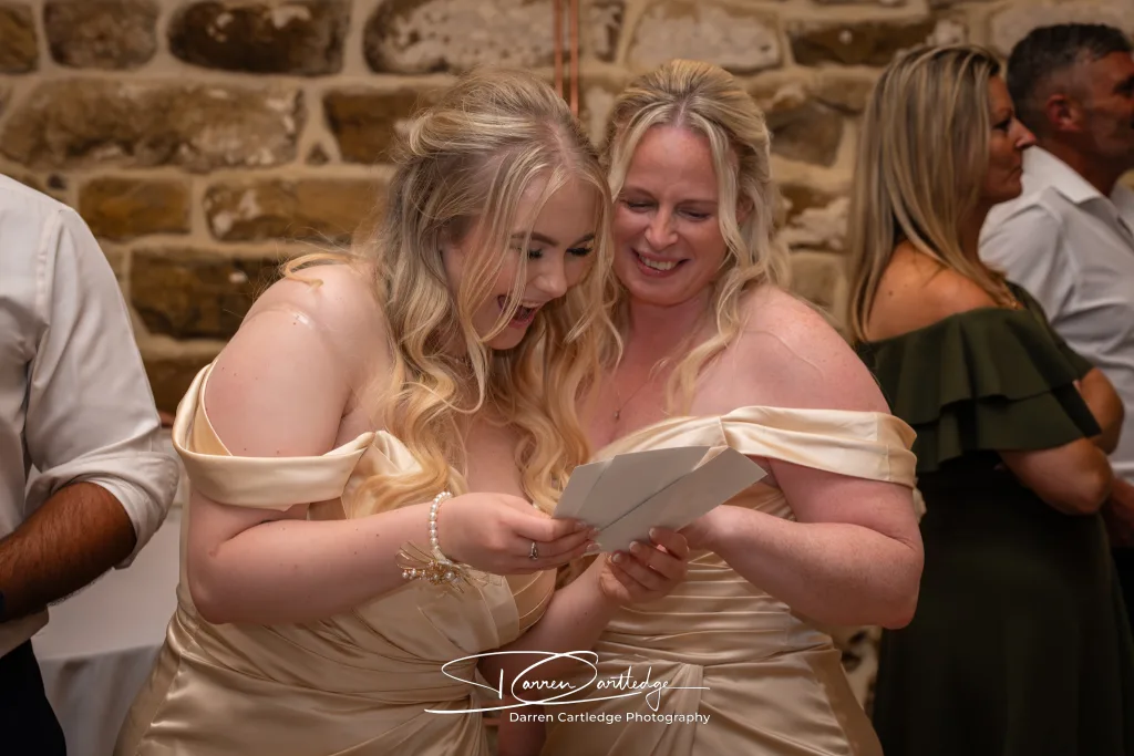 Bridesmaids laughing at photobooth pictures during a Yorkshire wedding