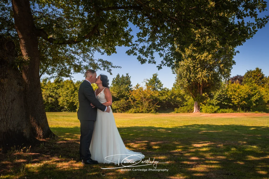 Bride and groom kissing under the shade of a tree during a Yorkshire wedding