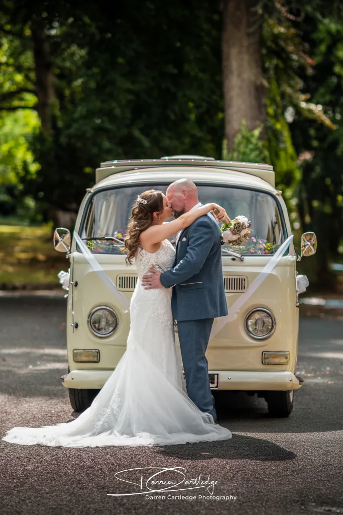 Bride and groom kissing in front of a VW camper during a Yorkshire wedding