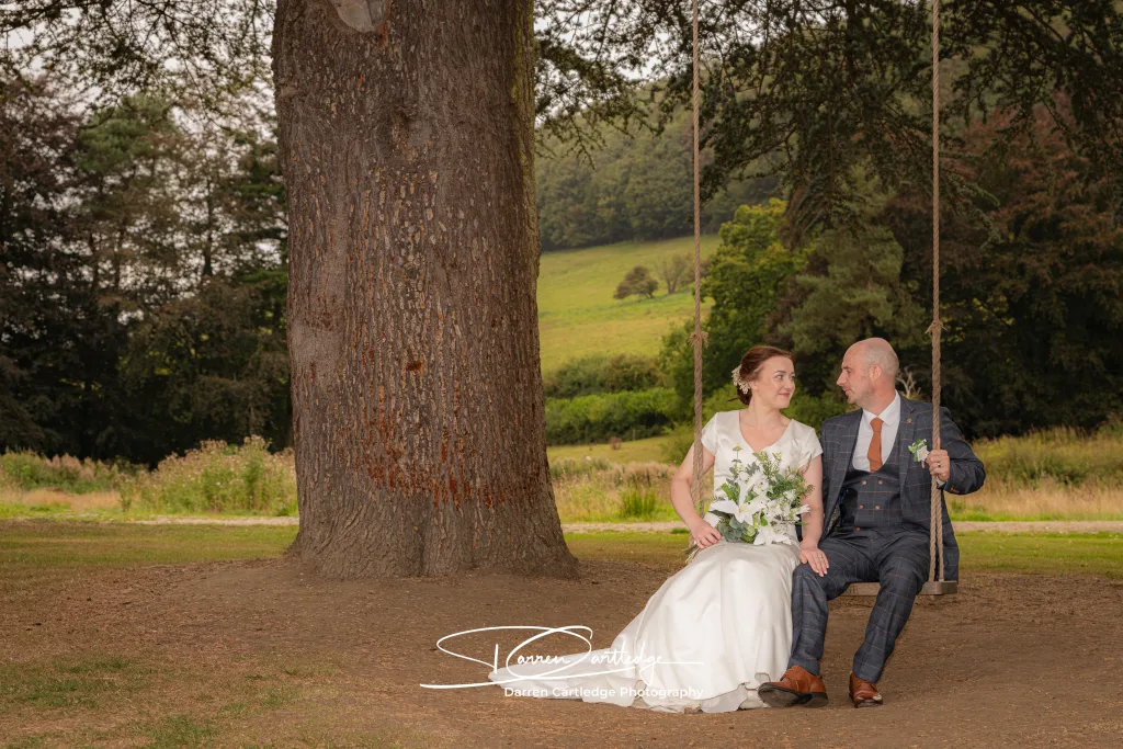 Bride and groom sitting on a swing at Hackness Grange during a Yorkshire wedding