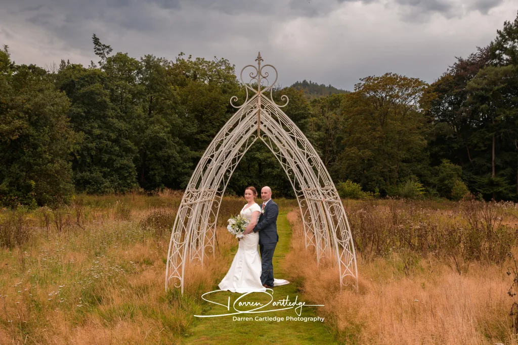 Bride and groom standing under the arch at Hackness Grange during a Yorkshire wedding