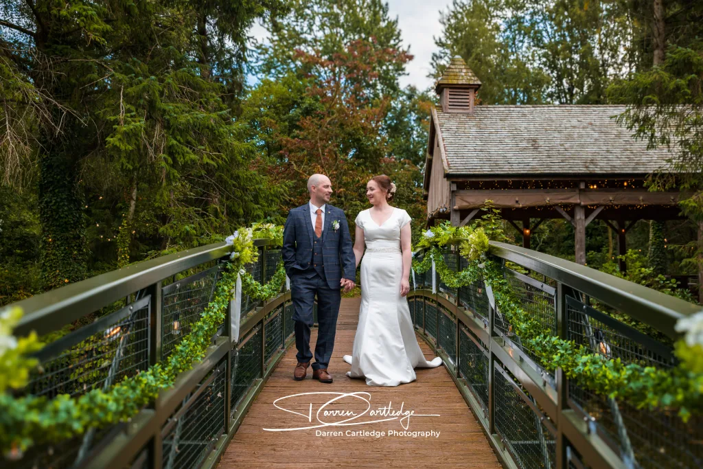 Bride and groom walking hand in hand over a bridge at Hackness Grange during a Yorkshire wedding