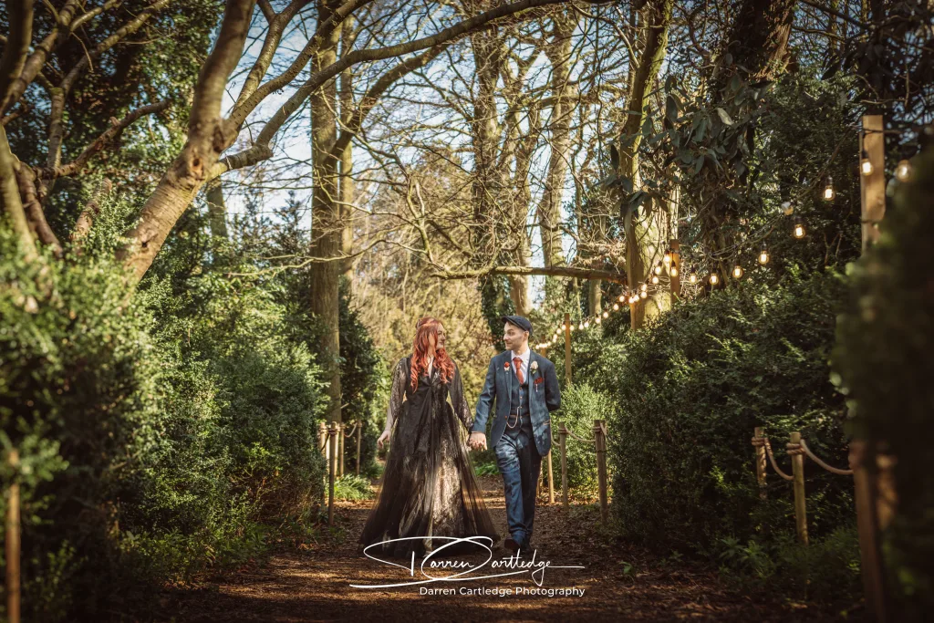 Bride and groom walking hand in hand along a woodland trail at Hazlewood Castle during a Yorkshire wedding