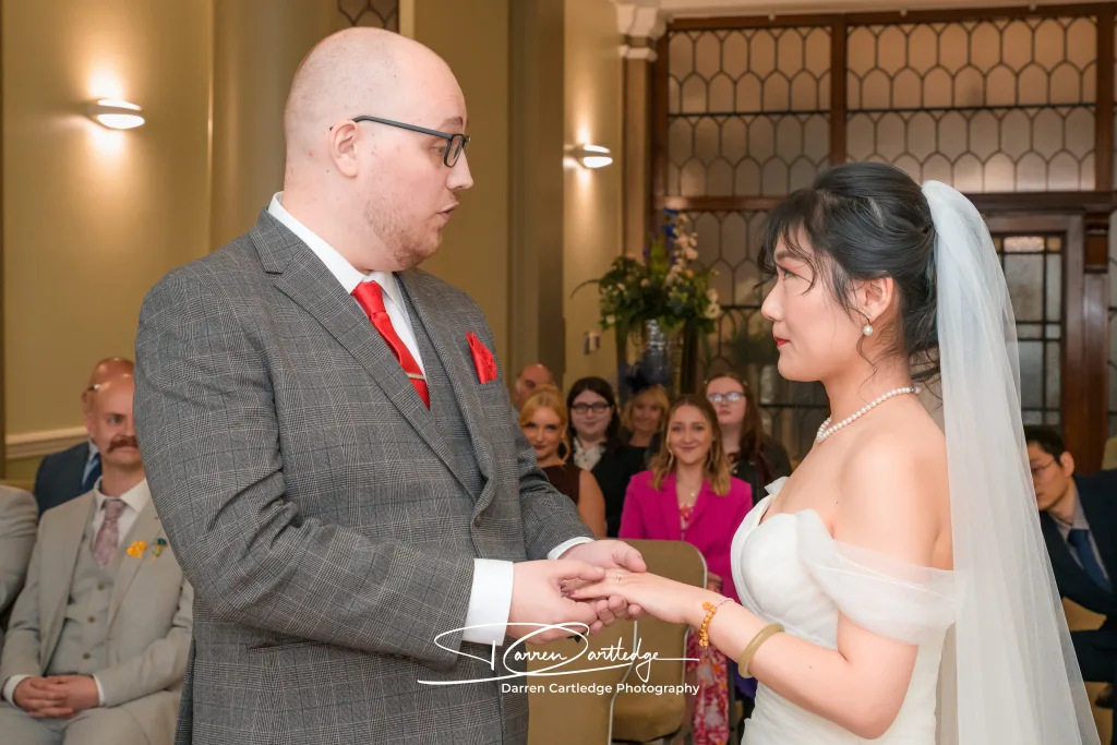 Groom holding bride’s hand during the ring exchange at a Yorkshire wedding ceremony