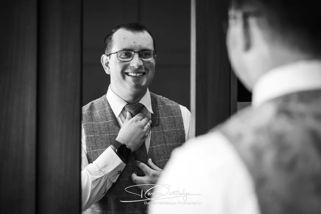 Groom getting ready in mirror reflection during morning preparations at a Yorkshire wedding