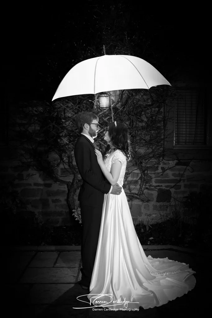 Bride and groom under an umbrella at night during a Yorkshire wedding