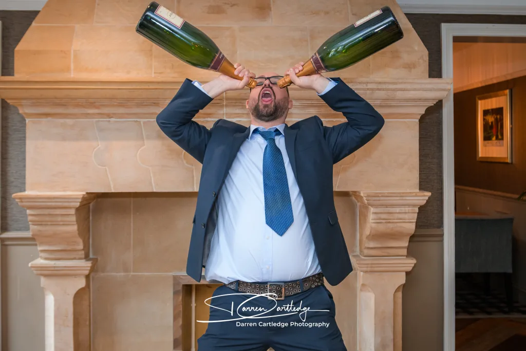 Wedding guest posing with giant champagne bottles during a Yorkshire wedding