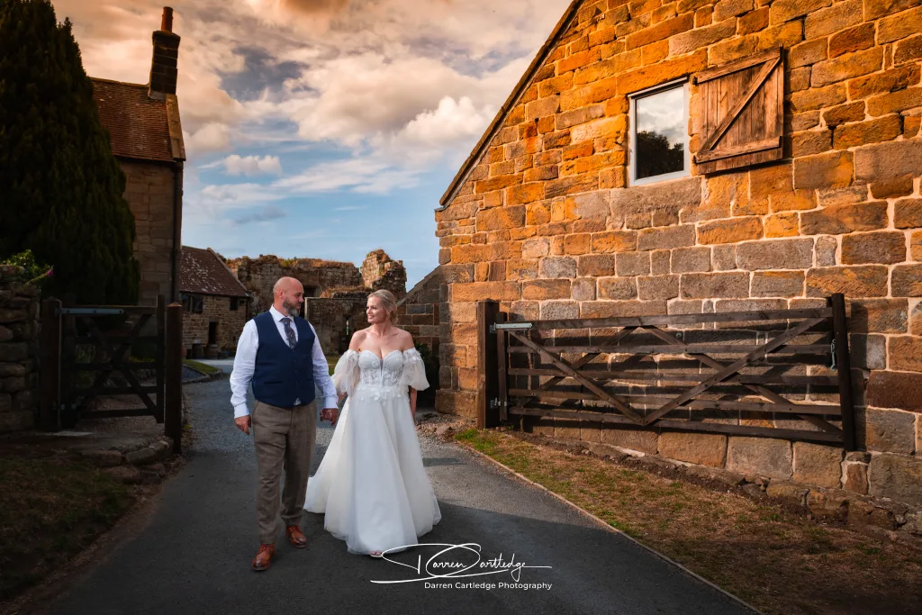 Bride and groom walking hand in hand during golden hour at Danby Castle during a Yorkshire wedding