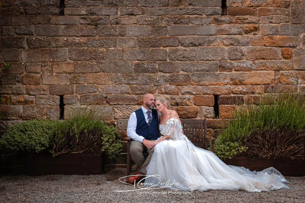 Couple portrait sitting on a bench at Danby Castle barn wedding in Yorkshire